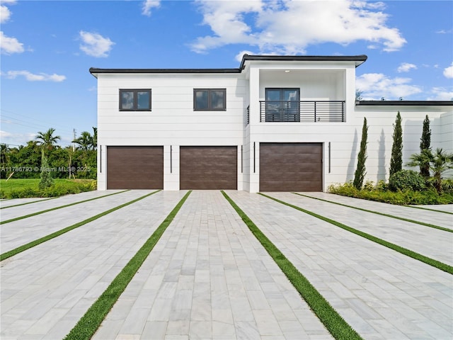contemporary house featuring an attached garage, driveway, and a balcony