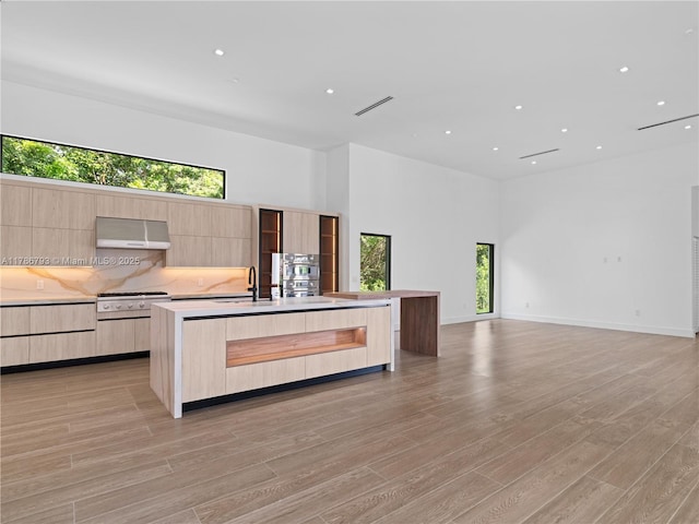 kitchen featuring extractor fan, light wood finished floors, light brown cabinets, and modern cabinets
