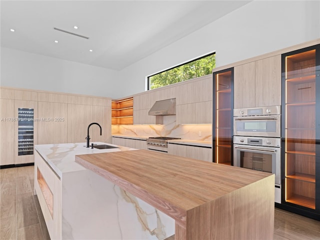 kitchen featuring modern cabinets, gas stove, exhaust hood, and a sink
