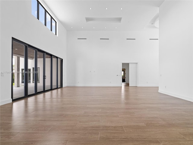empty room featuring wood finished floors and a towering ceiling
