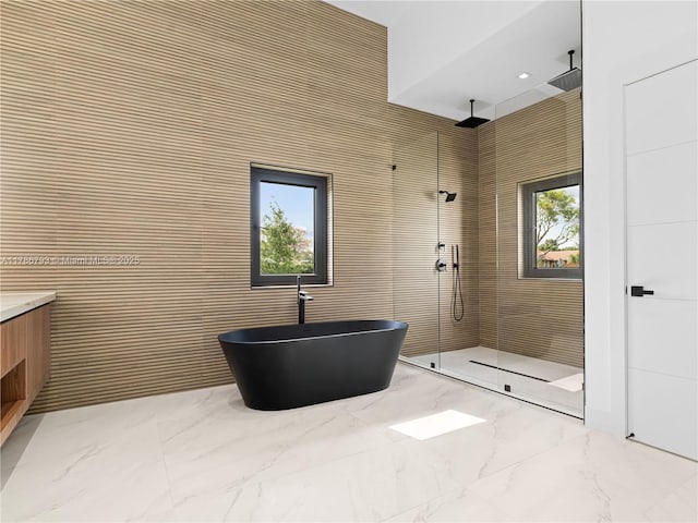 full bathroom featuring a freestanding bath, a tile shower, marble finish floor, and vanity