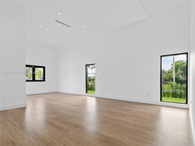 spare room featuring recessed lighting, a high ceiling, visible vents, and light wood-type flooring