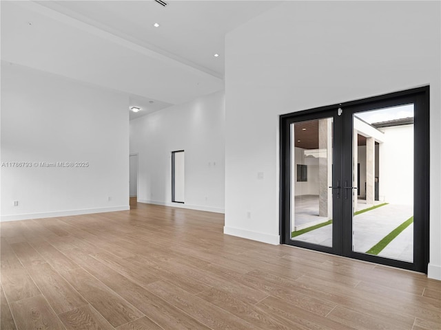 spare room featuring baseboards, recessed lighting, french doors, and light wood-type flooring