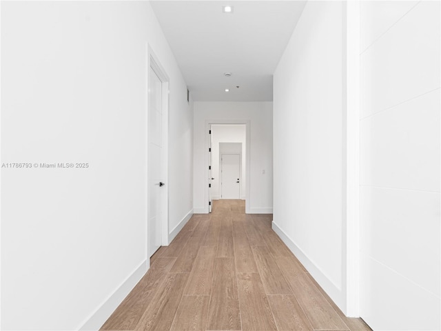 corridor featuring light wood-style flooring and baseboards