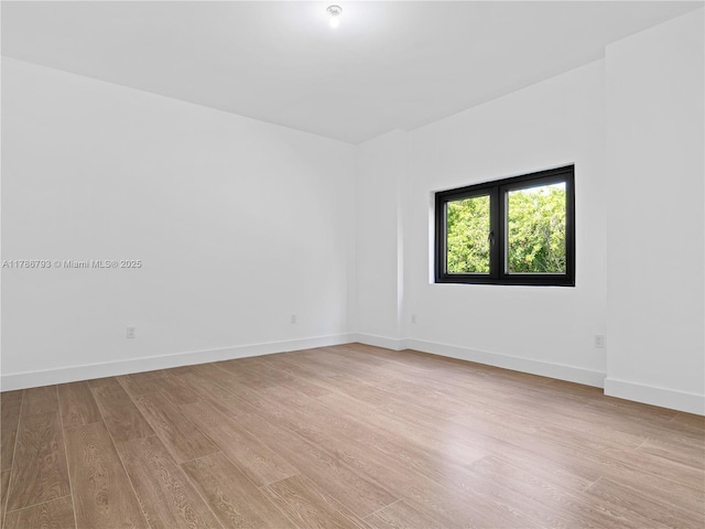 empty room featuring baseboards and light wood-style floors