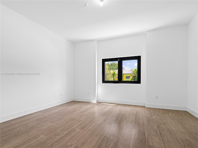 empty room with baseboards and wood finished floors