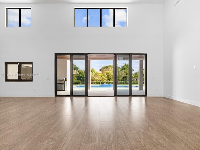 unfurnished living room featuring wood finished floors and a high ceiling