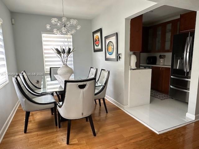 dining room featuring baseboards, a notable chandelier, and light wood-style flooring