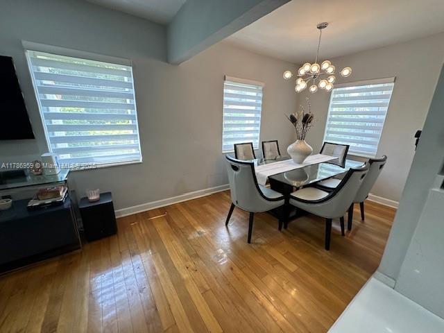 dining room with baseboards, light wood-style floors, and a notable chandelier