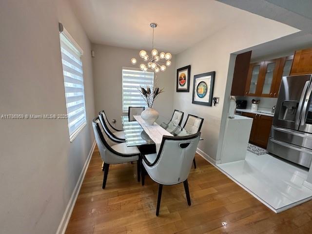 dining area featuring a chandelier, light wood-style floors, and baseboards