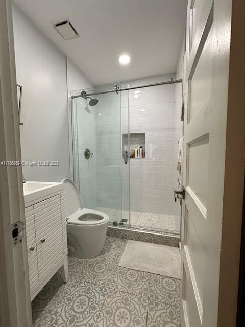 bathroom with a shower stall, vanity, toilet, tile patterned flooring, and visible vents
