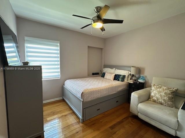 bedroom featuring baseboards, wood finished floors, and ceiling fan
