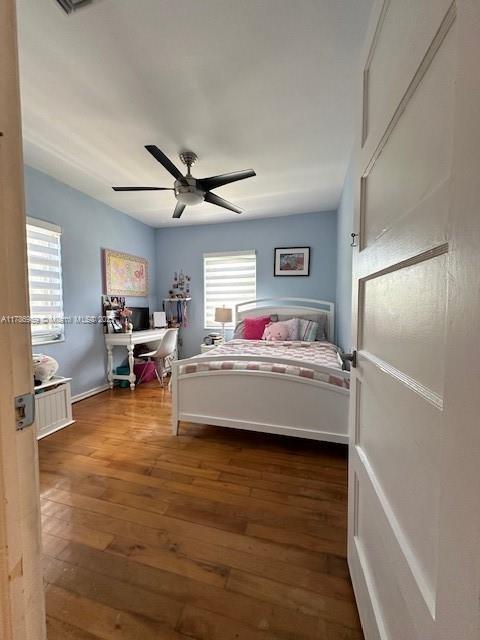 bedroom with baseboards, a ceiling fan, and dark wood-style floors