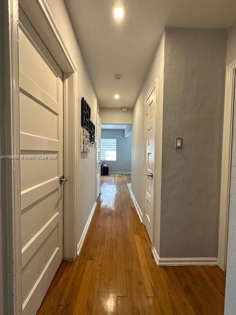 hallway with baseboards and dark wood-style floors