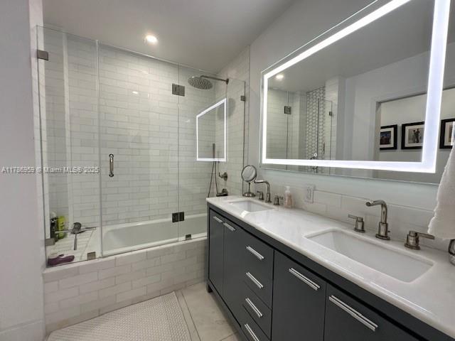 full bath with tile patterned flooring, a sink, tiled shower / bath, and double vanity