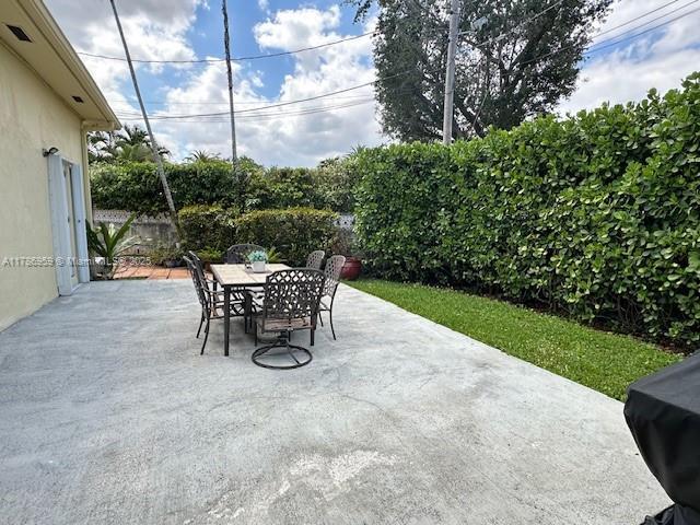 view of patio featuring a grill, fence, and outdoor dining space