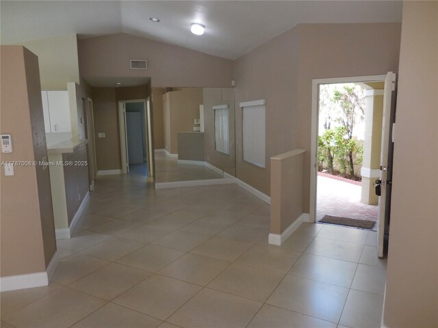 entrance foyer with visible vents, baseboards, light tile patterned flooring, and vaulted ceiling