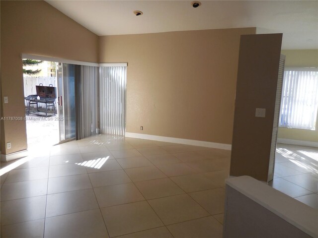 empty room with light tile patterned floors, baseboards, and vaulted ceiling