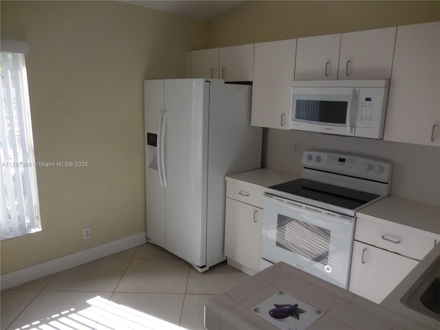 kitchen with white appliances, baseboards, light countertops, white cabinetry, and light tile patterned floors