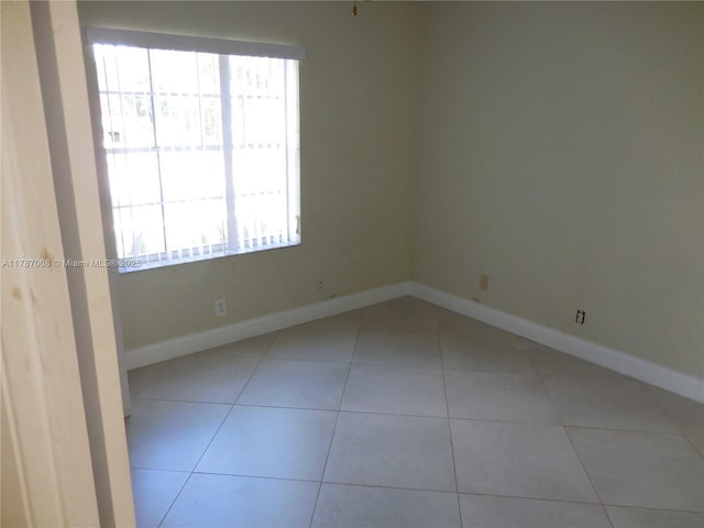 empty room featuring baseboards and tile patterned flooring