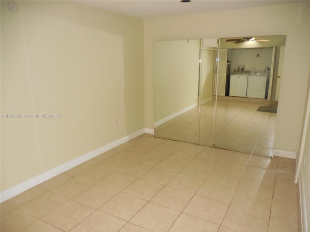 interior space with separate washer and dryer, a ceiling fan, baseboards, and light tile patterned floors