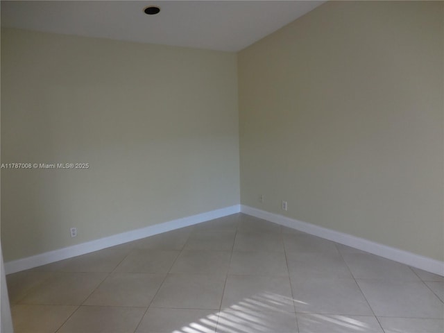unfurnished room with light tile patterned floors and baseboards
