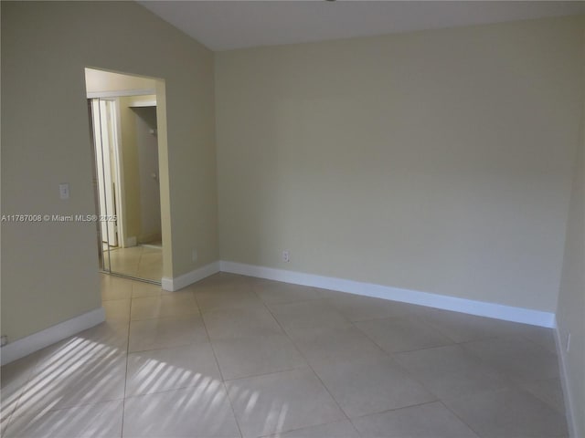 empty room featuring baseboards and light tile patterned floors