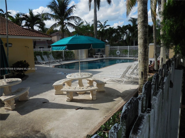 community pool with fence and a patio area