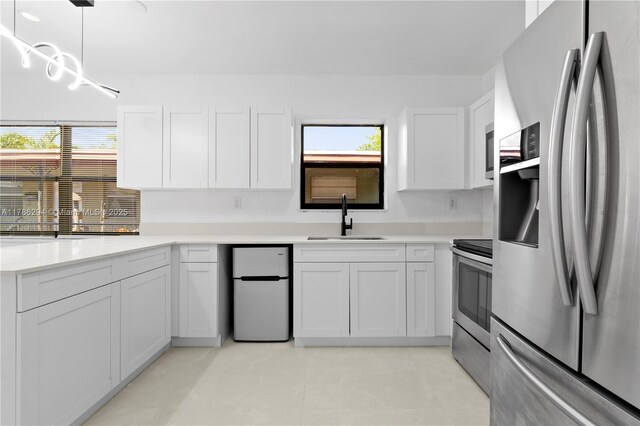 720 NW 6th St, Hallandale Beach, FL 33009 - kitchen featuring stainless steel appliances, a sink, white cabinetry, light countertops, and pendant lighting