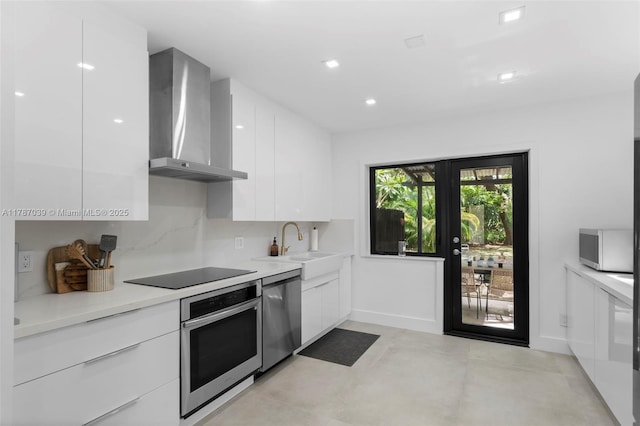 kitchen featuring wall chimney range hood, appliances with stainless steel finishes, and modern cabinets