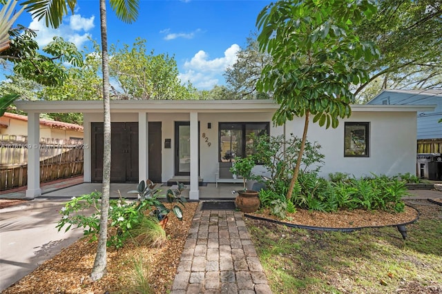 view of front of home with concrete driveway, fence, a porch, an attached carport, and stucco siding