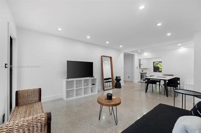 living area featuring baseboards, light speckled floor, and recessed lighting