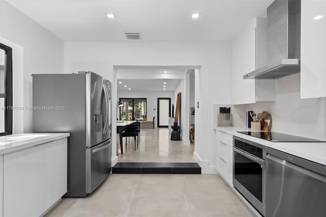 kitchen with wall chimney range hood, modern cabinets, stainless steel appliances, white cabinetry, and visible vents