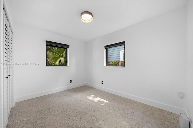 spare room featuring speckled floor and baseboards