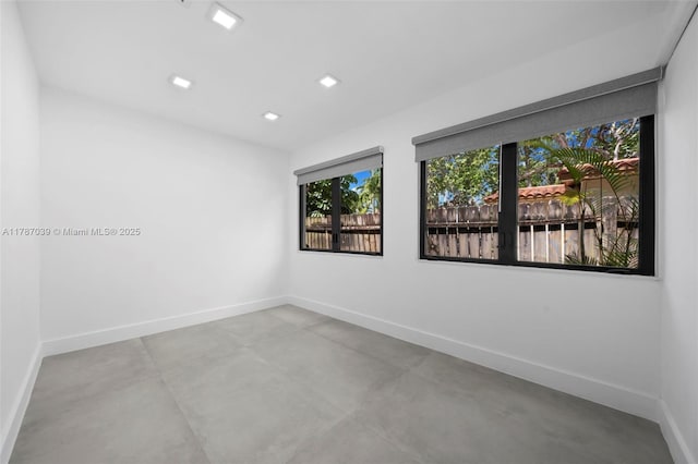 empty room with recessed lighting, concrete floors, and baseboards