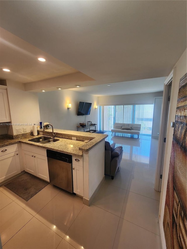 kitchen featuring light stone counters, a sink, open floor plan, dishwasher, and white cabinetry