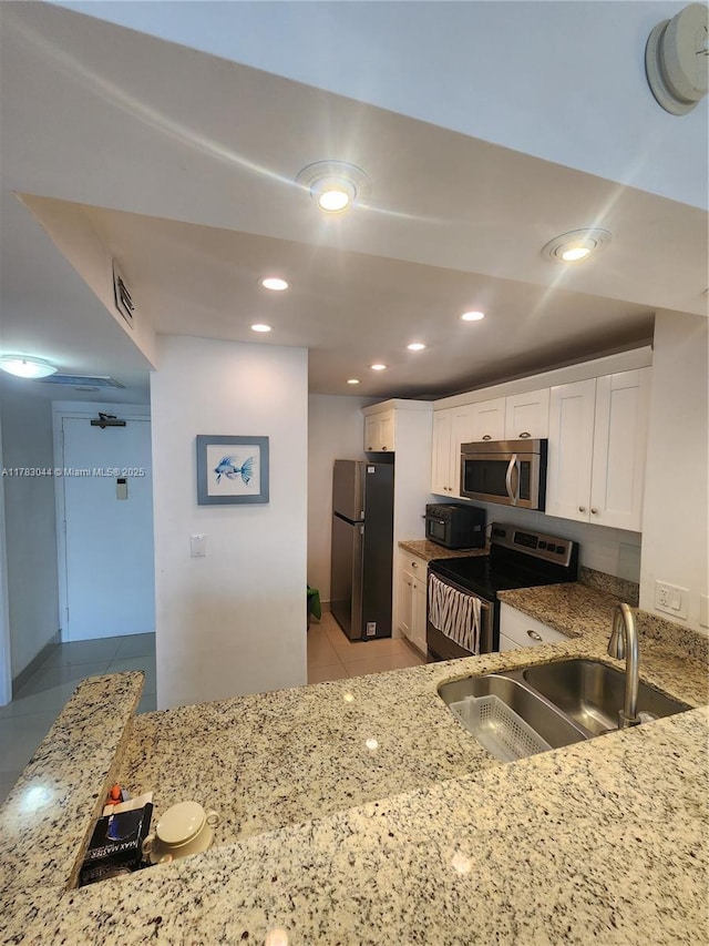 kitchen with light stone countertops, stainless steel appliances, a sink, and light tile patterned floors