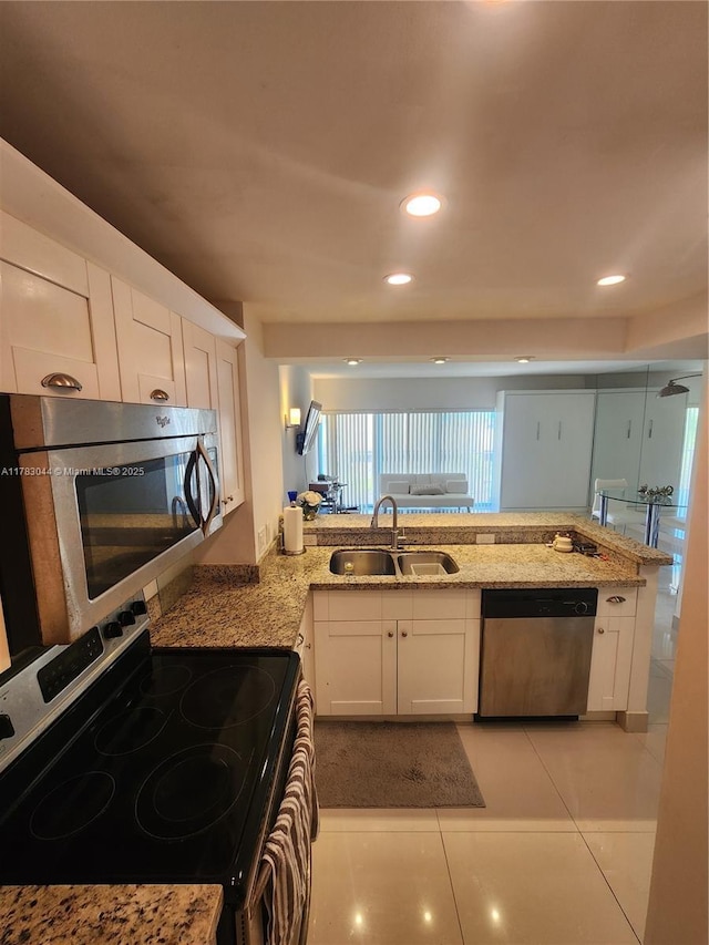 kitchen featuring light stone counters, a sink, white cabinetry, and appliances with stainless steel finishes