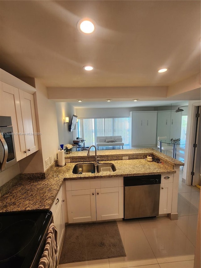 kitchen featuring recessed lighting, light stone counters, a sink, appliances with stainless steel finishes, and white cabinetry
