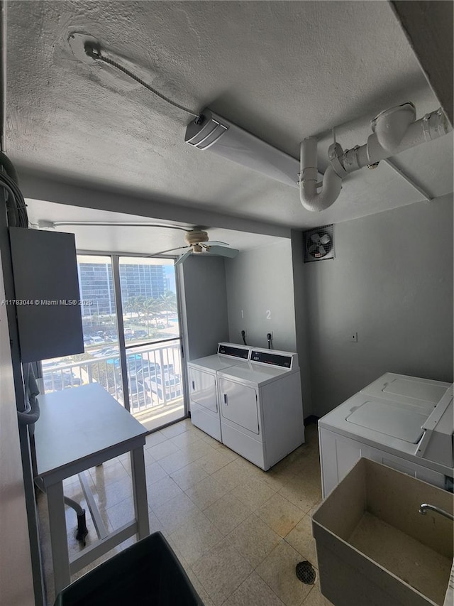 laundry room featuring a textured ceiling, a ceiling fan, a sink, and washer and clothes dryer