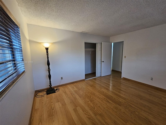 unfurnished bedroom with a closet, wood finished floors, and a textured ceiling