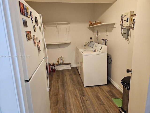 clothes washing area featuring dark wood finished floors, baseboards, laundry area, and separate washer and dryer