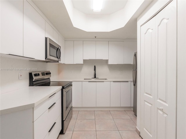 kitchen featuring a sink, light tile patterned flooring, white cabinetry, light countertops, and appliances with stainless steel finishes