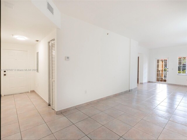 unfurnished room featuring baseboards, visible vents, and light tile patterned floors