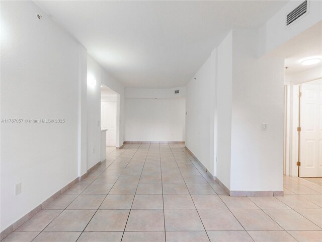 hall featuring visible vents, baseboards, and light tile patterned floors