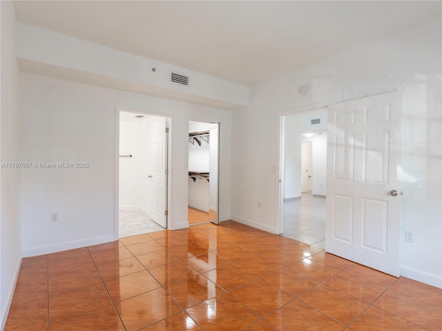 empty room featuring baseboards, tile patterned floors, and visible vents