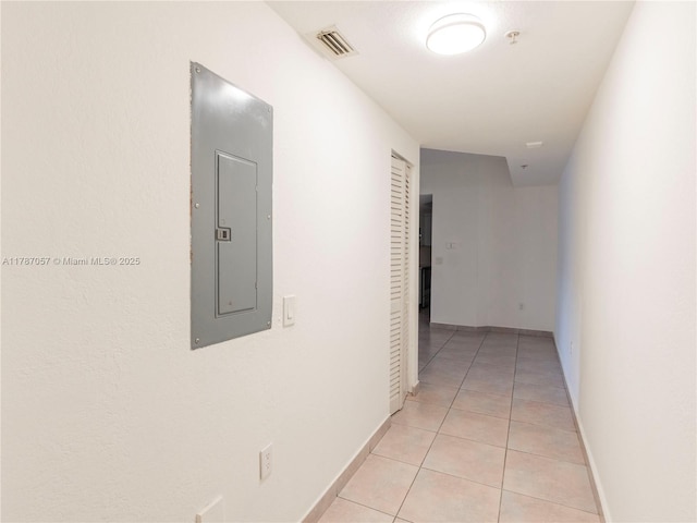 corridor featuring light tile patterned flooring, electric panel, baseboards, and visible vents