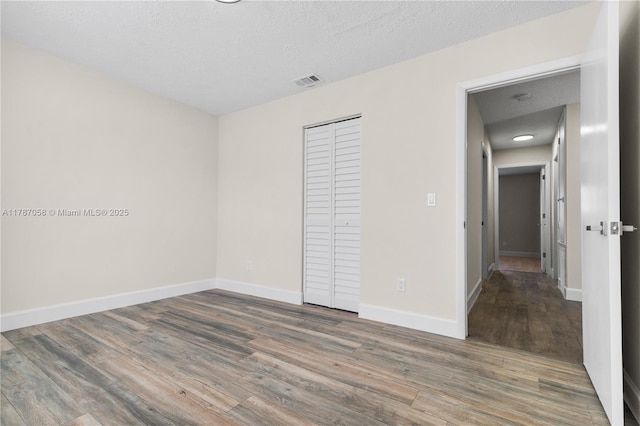461 SE Evans Ave, Port St Lucie, FL 34984 - unfurnished bedroom featuring wood finished floors, a closet, baseboards, and a textured ceiling
