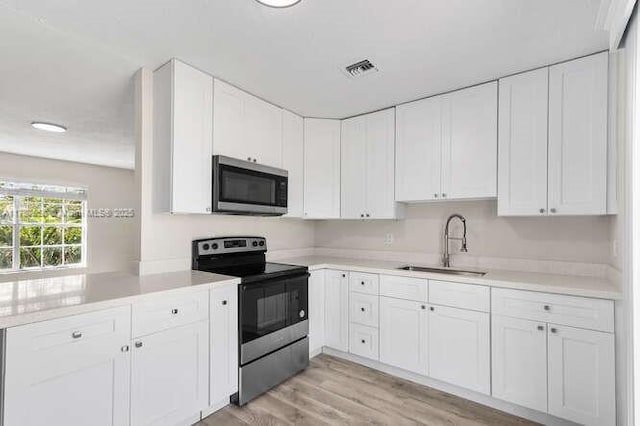 461 SE Evans Ave, Port St Lucie, FL 34984 - kitchen featuring stainless steel appliances, a sink, white cabinets, and light countertops