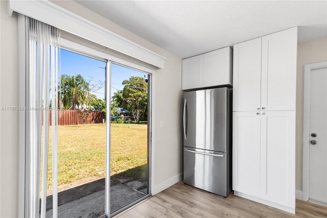 461 SE Evans Ave, Port St Lucie, FL 34984 - kitchen featuring freestanding refrigerator, light wood finished floors, white cabinets, and baseboards